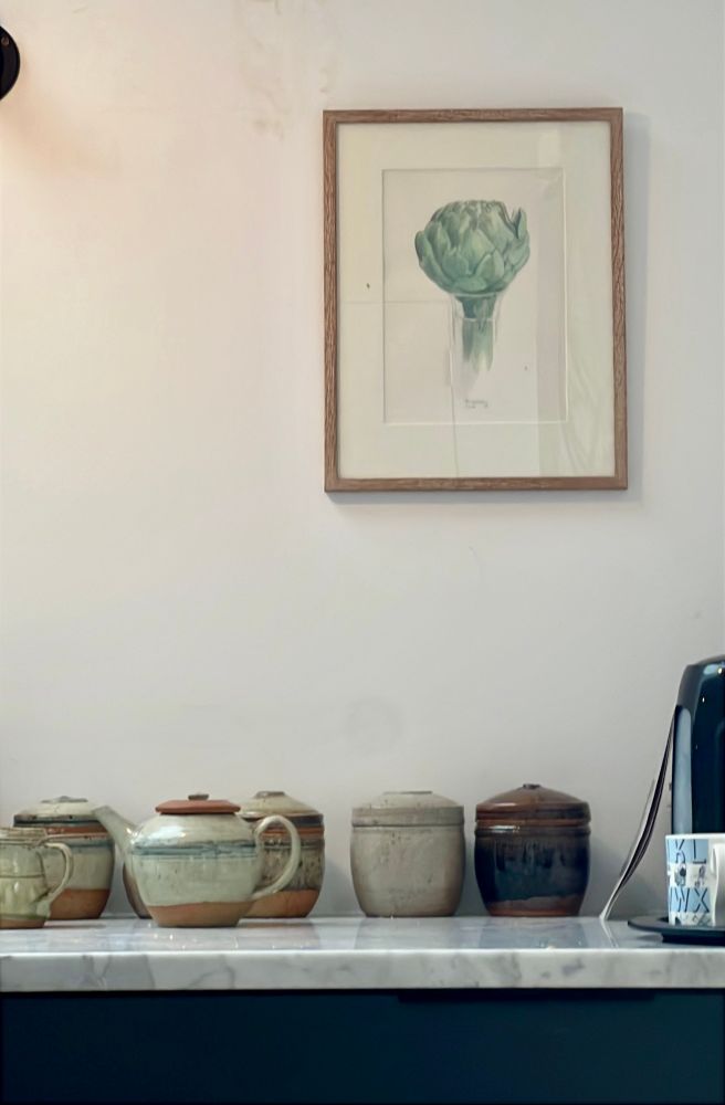 Richard Batterham pots and teapot and jug on a marble worktop under a painting of an artichoke 