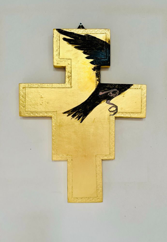 A cross of gold with a crow flying off 