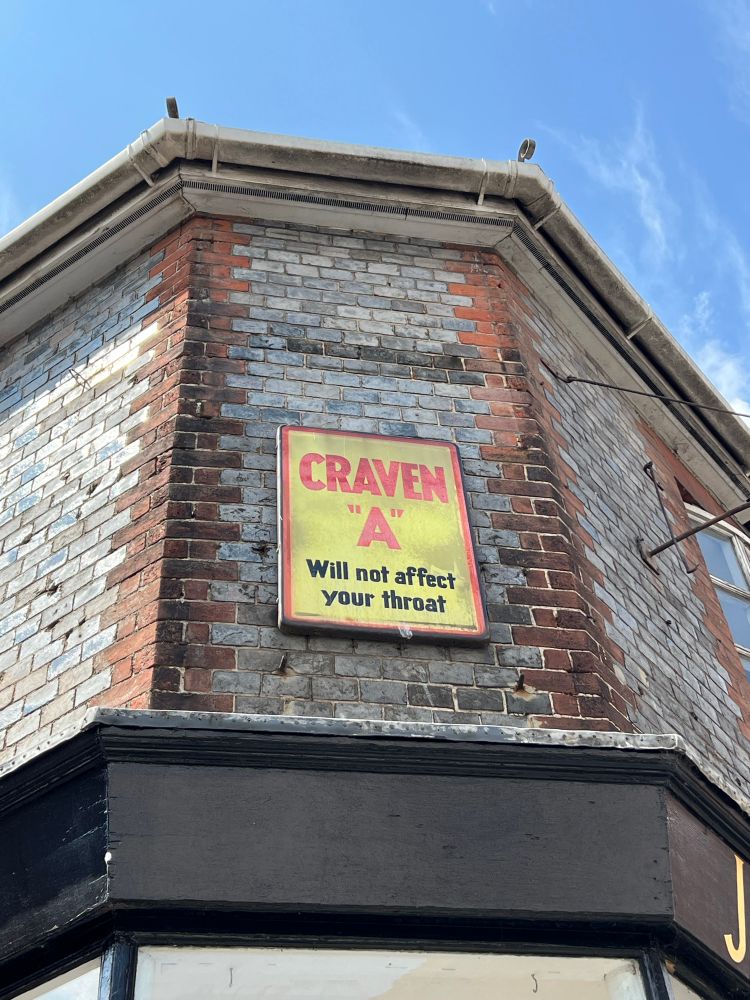 A yellow enamel sign with red lettering reads Craven A will not affect your throat 