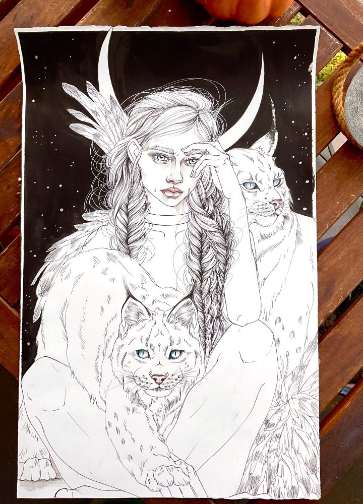 pen and ink drawing of the goddess freya. She sits cross-legged on the ground wearing her cloak of hawk feathers, under a sliver of a moon and surrounded by her two wildcats (depicted as lynx).