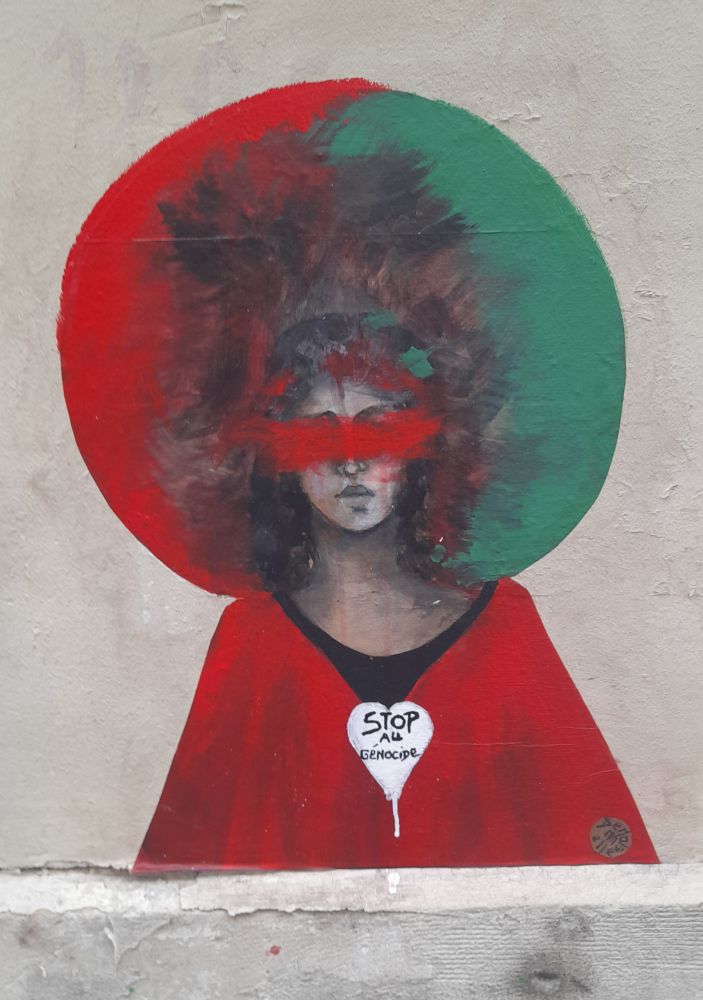 Street art : une femme aux couleurs palestiniennes, les yeux masqués par un bande rouge sang, avec dans un cœur blanc sur sa poitrine 