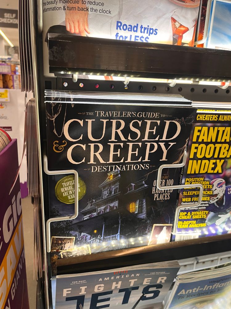 Photo of a magazine in a grocery store checkout rack. It is titled "Cursed & Creepy Destinations" and has a picture of a creepy Victorian home at night 