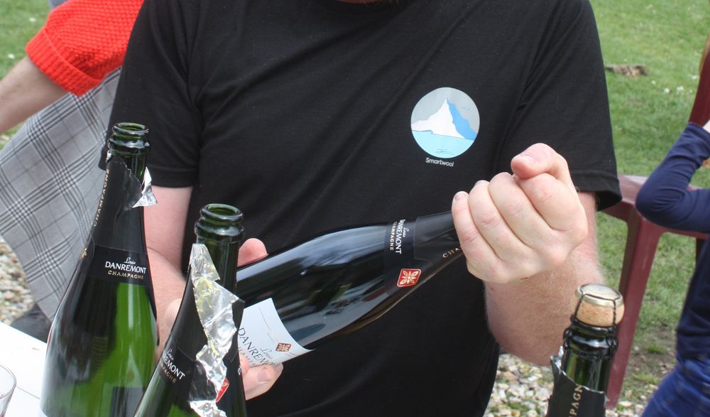 Gros plan sur les mains du spécialiste en train de déboucher le champagne. Ne vous inquiétez pas ce sera avec modération (il faut le dire).