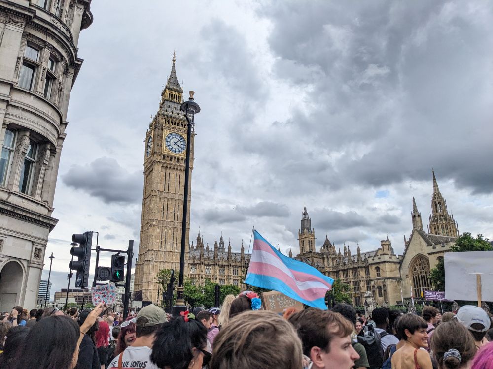 Trans pride flag in front of Big Ben and Parliament