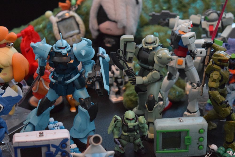 a closer photo of a bunch of toys, plush dolls, and figures on a table. it looks chaotic but fun at the same time.