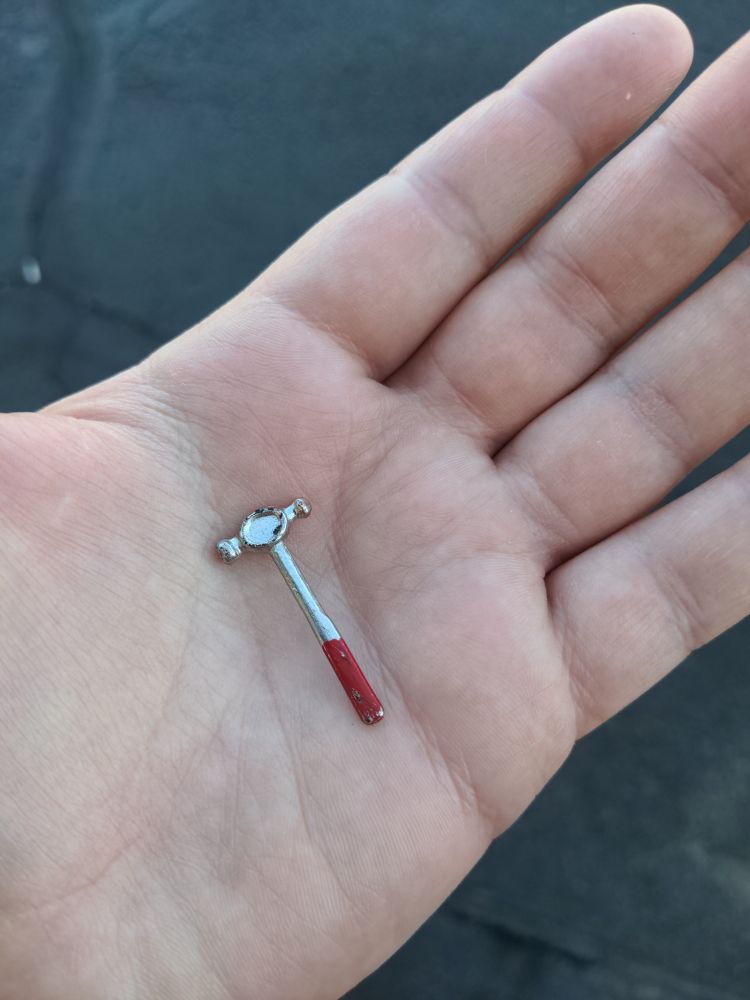 A tiny hammer, left on a curb, presumably by a blue-collar fairy