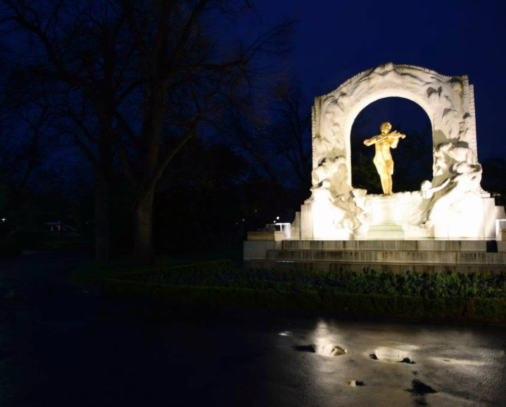 Johan Strauß Denkmal im Stadpark in Wien. Hell beleuchtete Figur mit Violine 