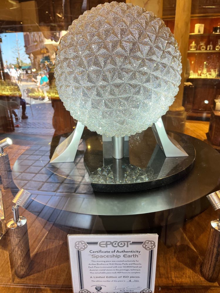 A jewel-encrusted Spaceship Earth inside a glass display case in a World Showcase shop.