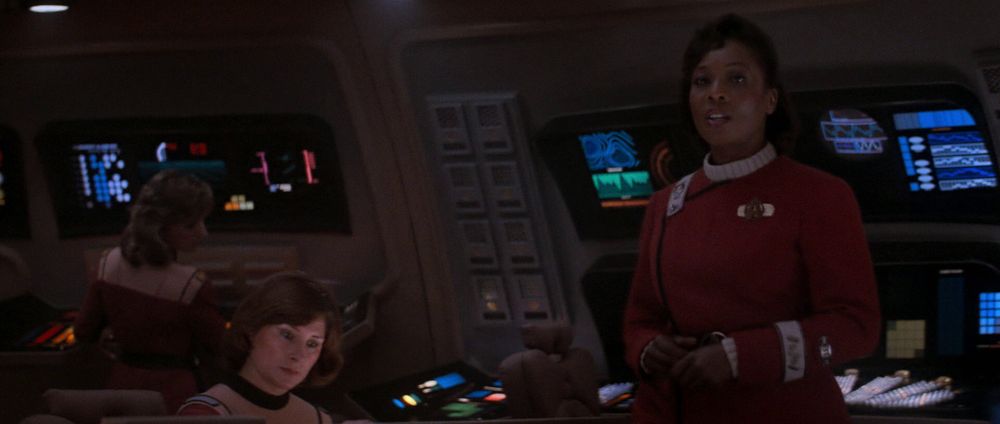 Screenshot from the opening scene of Star Trek IV, with Captain Sinclair on the bridge of the USS Saratoga. The set is more dimly lit than before, while the displays are backlit more brightly.
