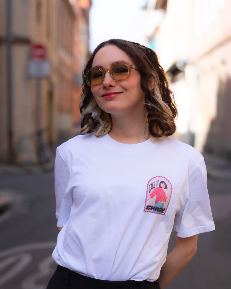 T-Shirt Take Up Space, avec sur le coeur une illustration d’une femme poussant les cadres qu’on lui impose 