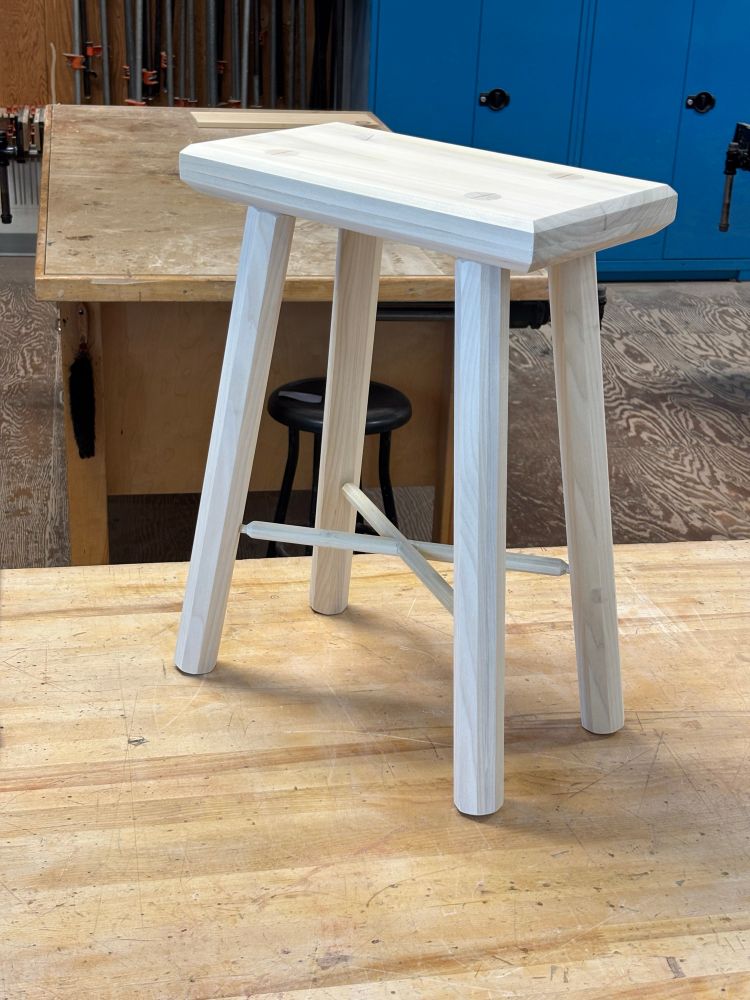 Isometric view of a traditional staked stool on a bench in a shop class. 