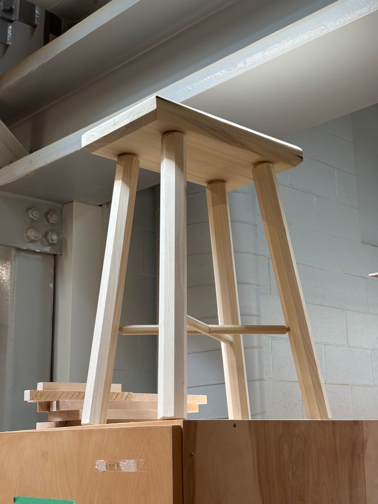 Low angle with angelic lighting on a traditional staked stool. 4 octagonal legs support an equirectangular seat. 