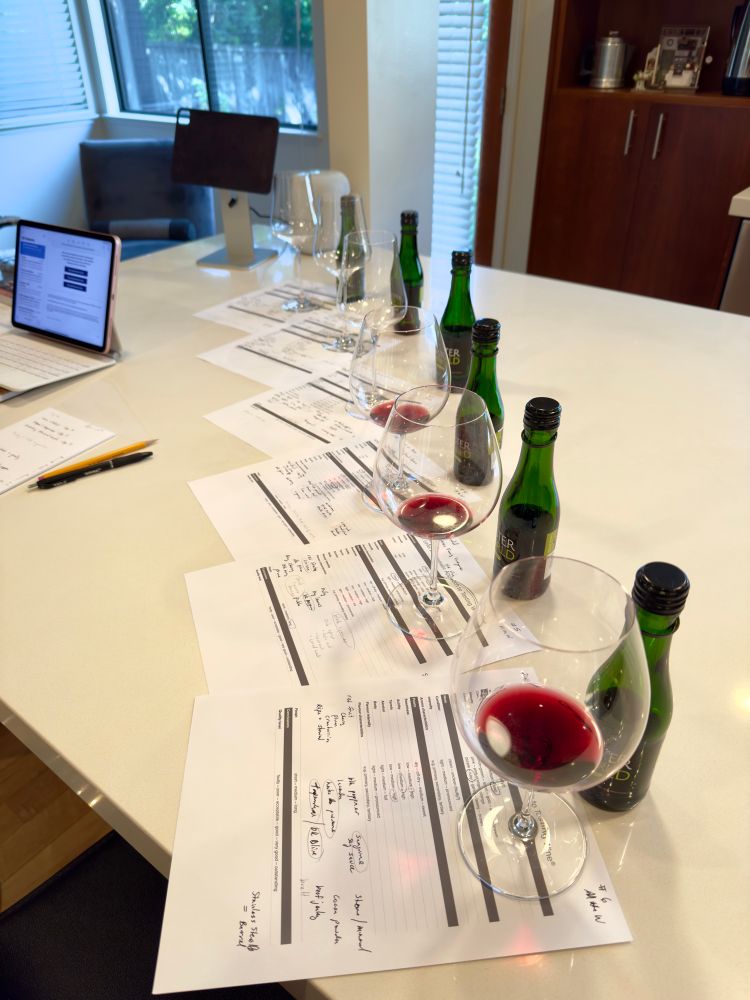 Several wine glasses with wine sitting on pieces of paper with writing. 