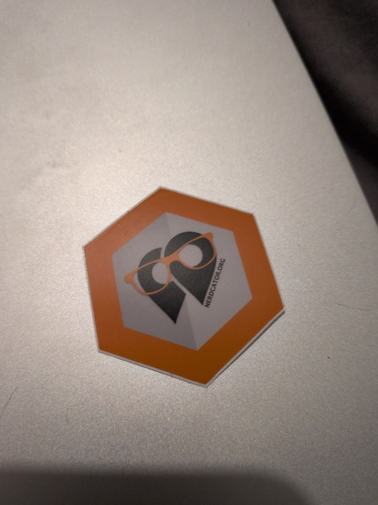 A hex Sticker with two location pins close to each other, "wearing glasses" the text reads nerdcator.org