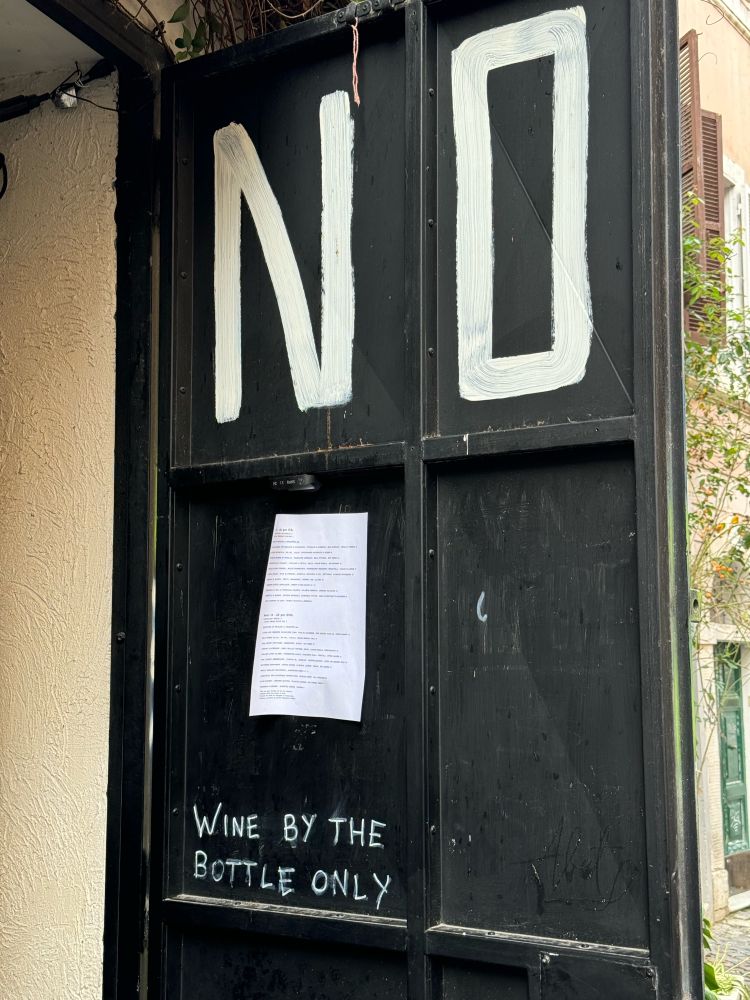 Roman door says Wine by the Bottle Only