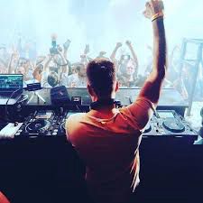 DJ with hand raised, over looking crowd