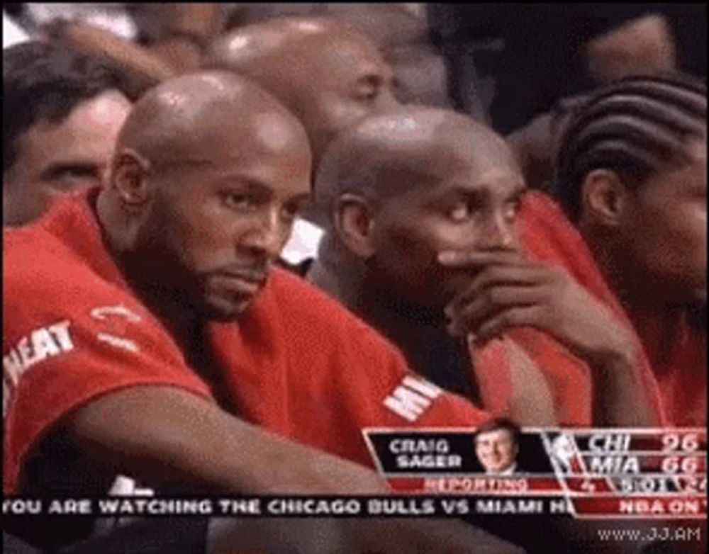 a group of men sitting in a stadium watching a basketball game .