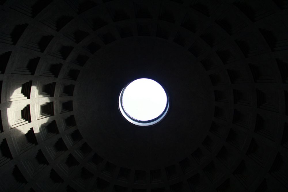 monochrome: dark, a bright centered circle casts a spotlight on the inside of a gridded dome that fades away into blackness