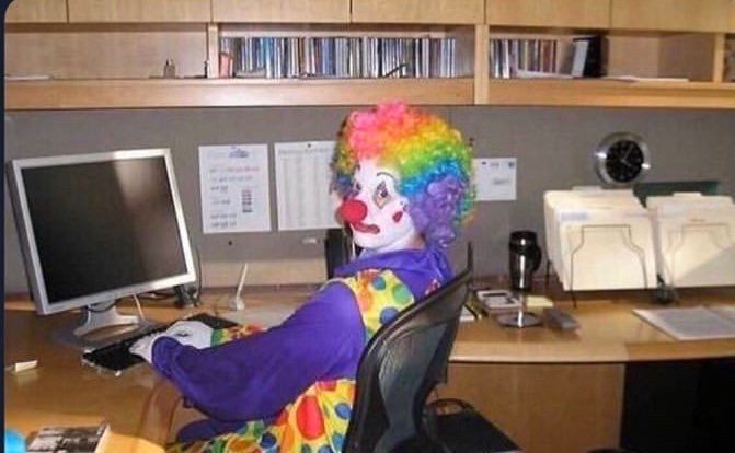 clown sitting at desk looking back at camera