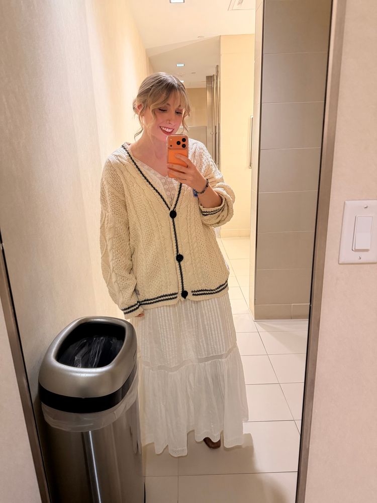 Blonde Woman dressed in a white linen dress in the original Taylor Swift Folklore cardigan