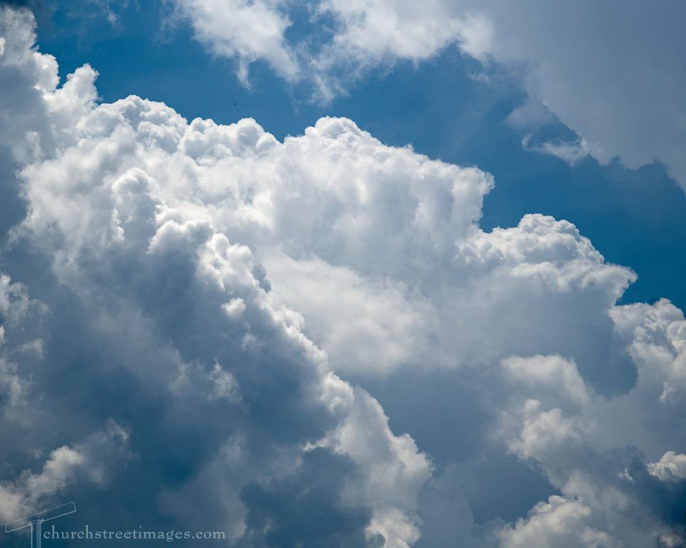 Piles of summer rain clouds with a scrap of blue sky showing through