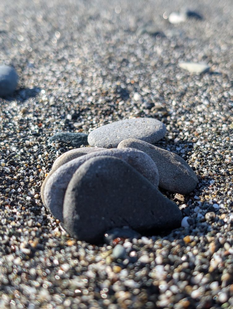 Rocks on a bed of sand at the ocean.