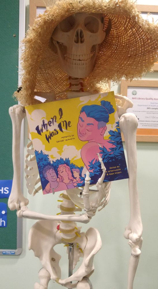 Photograph of a skeleton holding a book titled "When I Was Me"