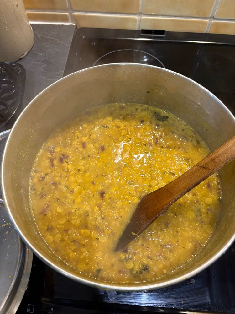 Bubbling pot of yellow dal with bits in it
