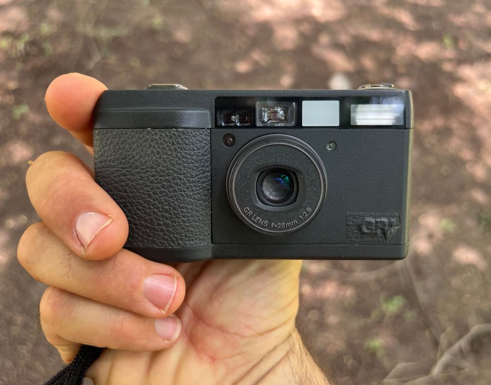 A Ricoh gr1 held in my hand. The gr1 is blacked out. 