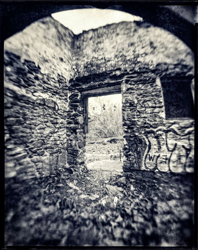 A black and white photo of a doorway in a ruined building. 