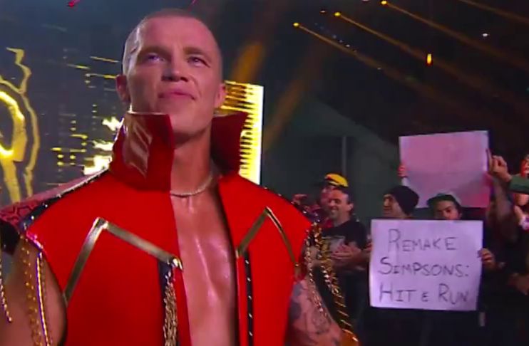 sign from AEW Grand Slam in Australia showing a fan holding a sign that reads REMAKE SIMPSONS: HIT & RUN while Kyle Fletcher looks happy and slutty 
