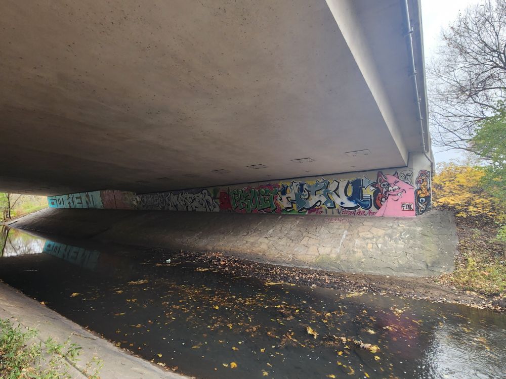Underside of a bridge covered in colorful graffiti 