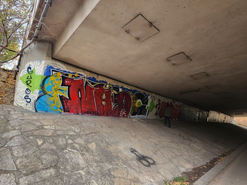 Underside of a bridge covered in colorful graffiti