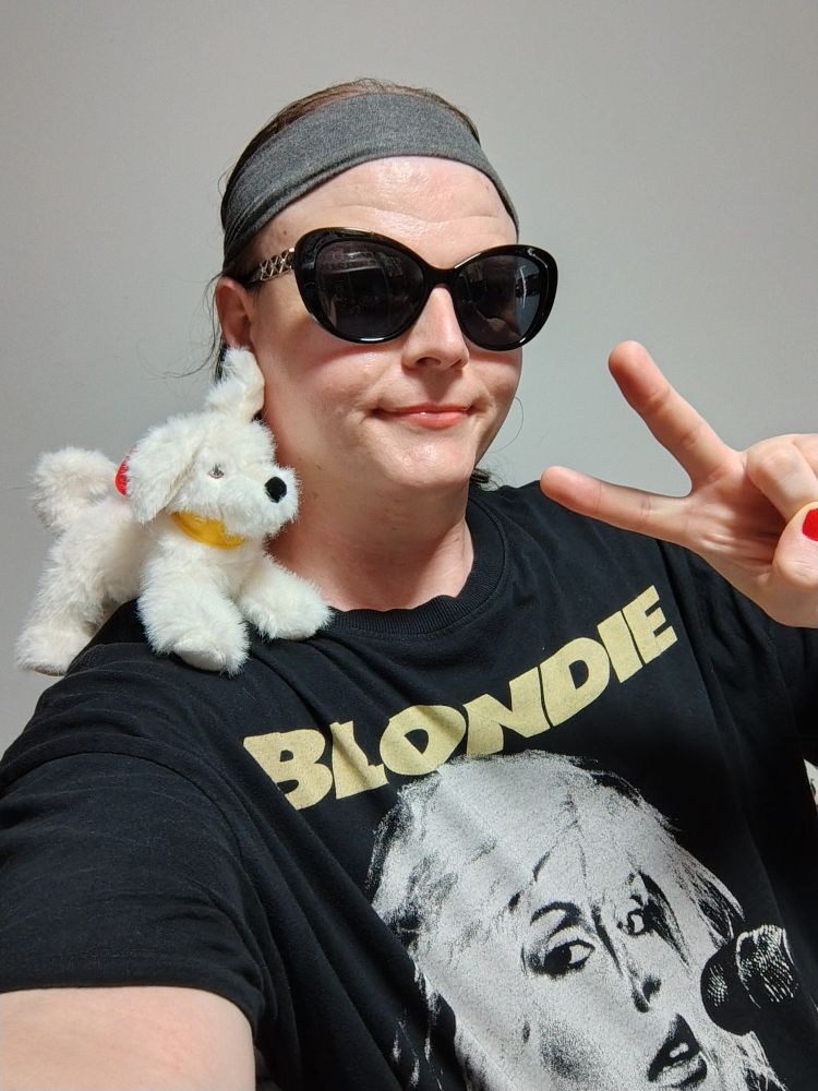 Roxy myself posing with peace sign with sunglasses on, pink lipstick with Blondie shirt and little Krypto plush on my shoulder.