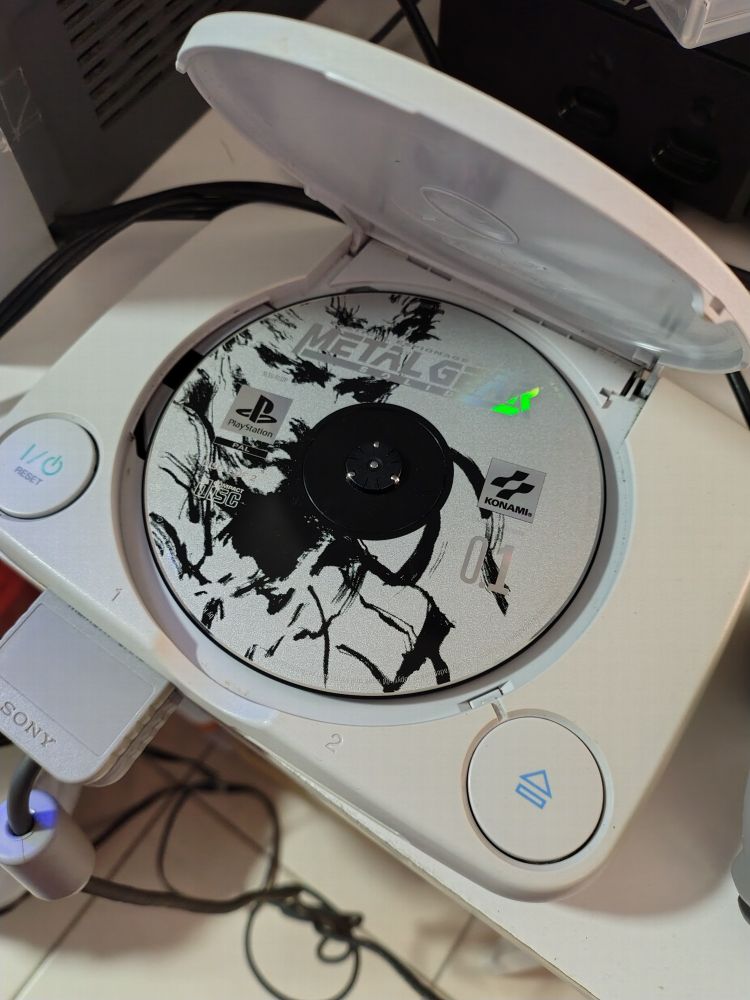 A psone console with open lid with Metal Gear Solid disc 1.