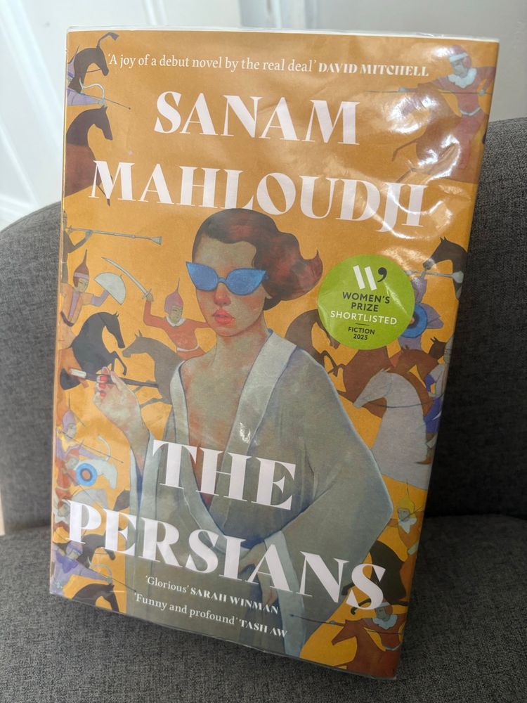 Book cover of The Persians by Sanam Mahloudh. Yellow background with an elegant woman in foreground wearing a gown/ jacket slipping off one shoulder. In the background are images of Persian battles/ warriors on horseback 