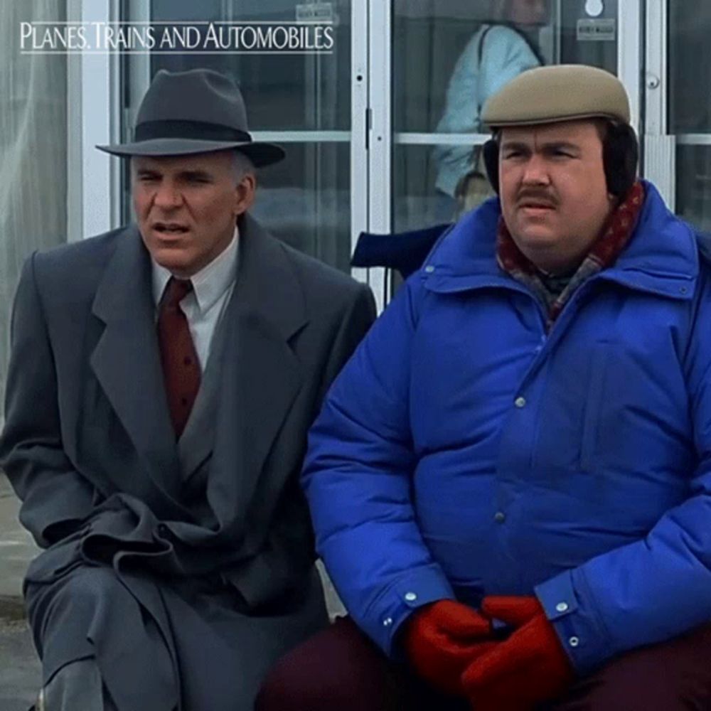 two men are sitting in front of a door that says planes trains and automobiles on it