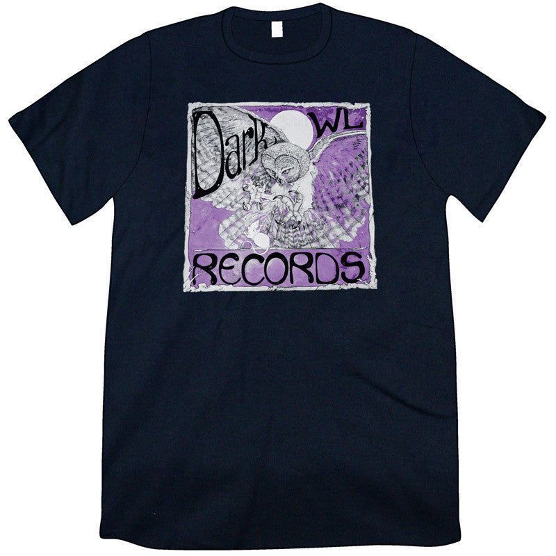 A black t-shirt: across the front is a square with a white border and a purple background. over this is an an owl, wings spread as if about to land. Above and across the wings are the words: Dark Owl. The "O" in owl is a moon. At the bottom is the word "Records."