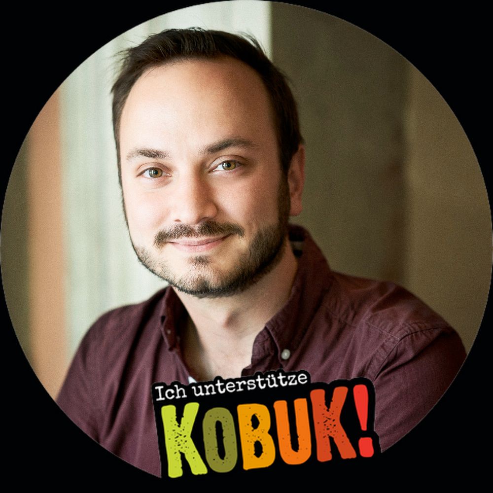 Mein Profilbild. Lächelnd. Umrandet mit einer "Ich unterstütze KOBUK!" Vignette.