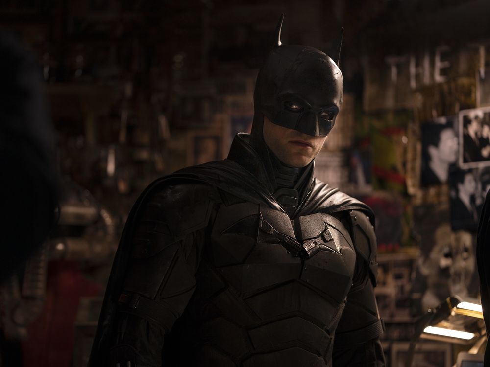 Promotional image from The Batman (2022). Batman stands in front of Riddler’s “murder board”, consisting of numerous newspaper clippings and stock photographs.