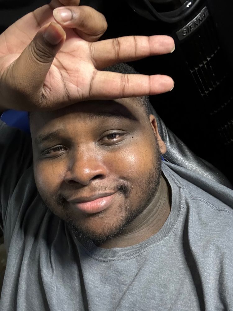 Extell in a grey shirt, holding up the peace sign