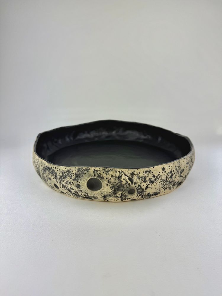 MoonMoon Ceramics, artist is Karleigh Thompson.

This is a large ceramic moon serving dish. 

The outside of this stunning serving dish has been hand sculpted to look like the surface of a moon. Textured with craters and rock surface. 

Made of white stoneware, stained black outside, and the inside is glazed in matte black.