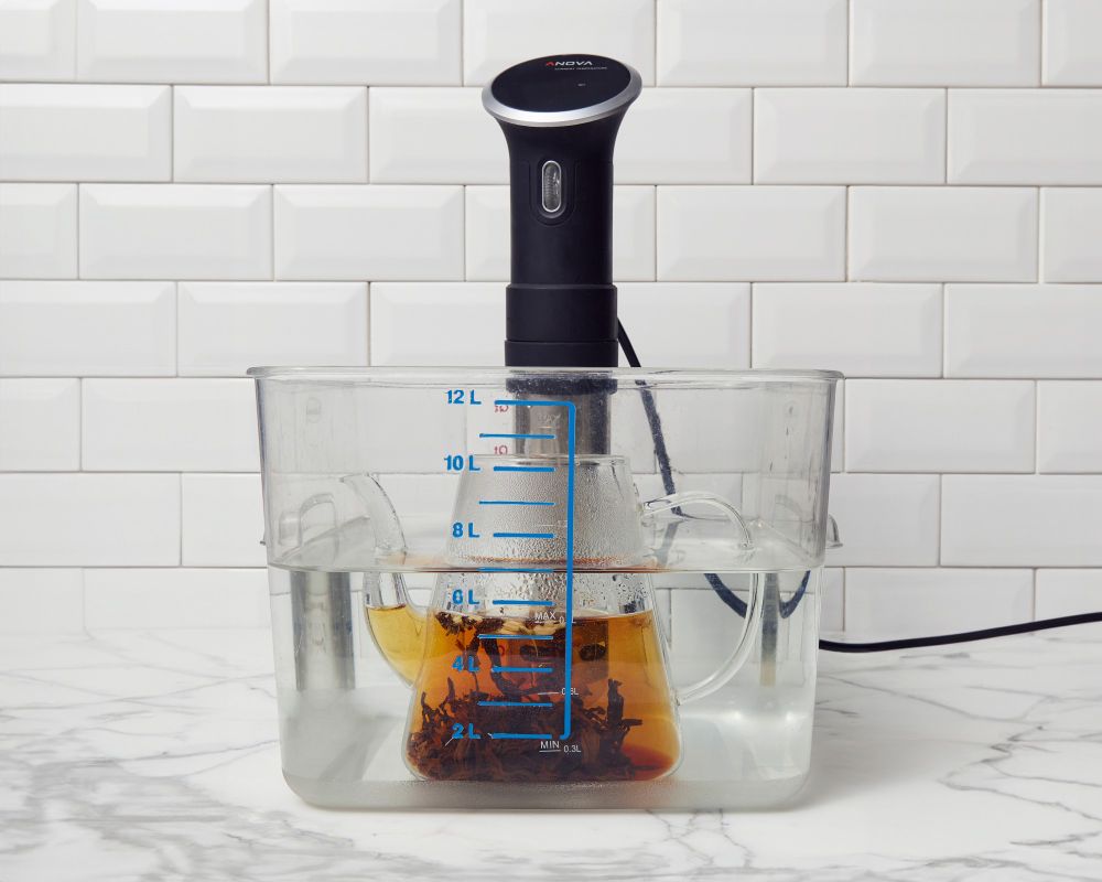 Glass tea pot with tea brewing in it in a constant temperature bath.