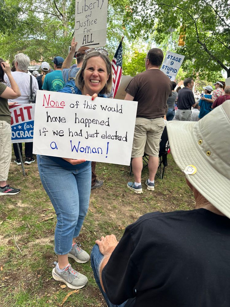 Woman with protest signs “none of this would have happened if we just elected a Woman”