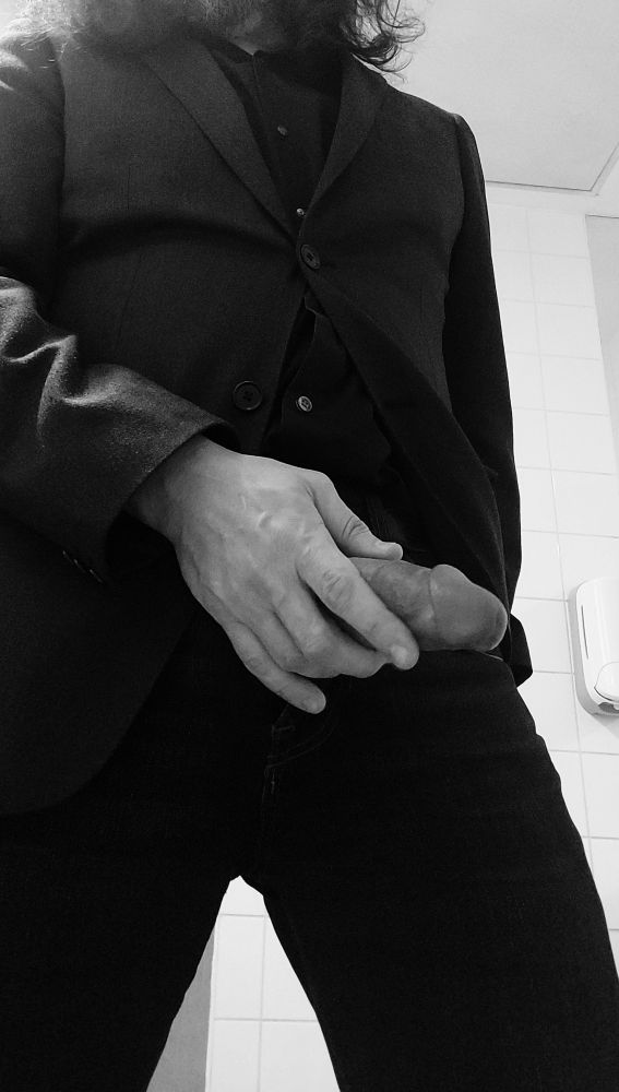 Black suit. Hand holding hard cock out of the pants