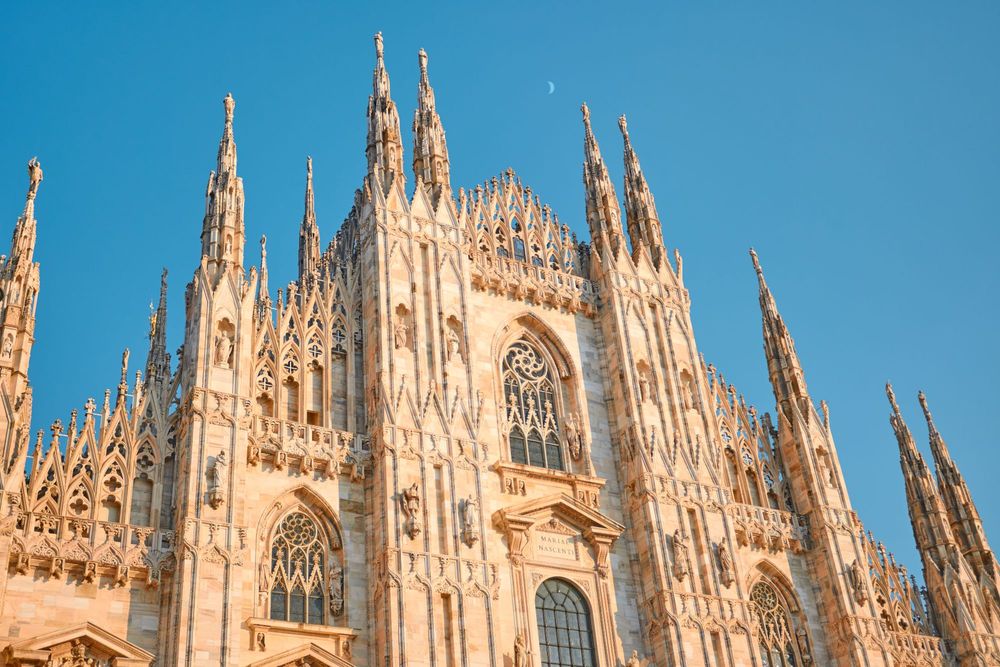 Milano Cathedral. Gothic cathedral facade with spires against a blue sky.
