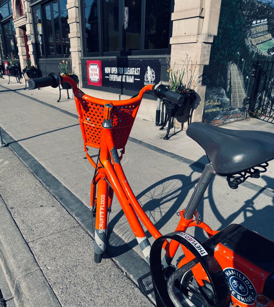 An orange bikeshare bike with the name Scruffy Flood