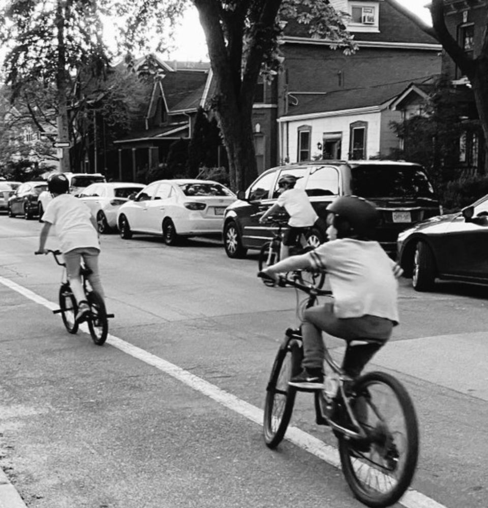 3 kids on bikes on the street in b/w