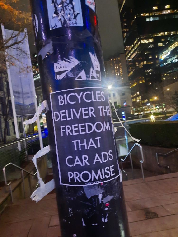 Black and white poster on the city pole bicycles deliver the freedom that auto ads promise