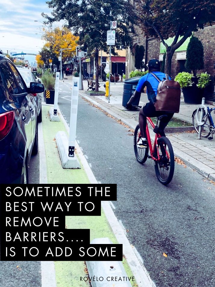 person biking in a protected bike lane on a city street.

Sometimes the best way to remove barriers is to add some 